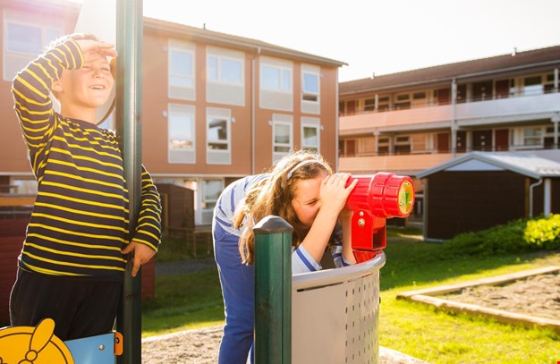 2 barn som leker på lekeplass utenfor leiligheter